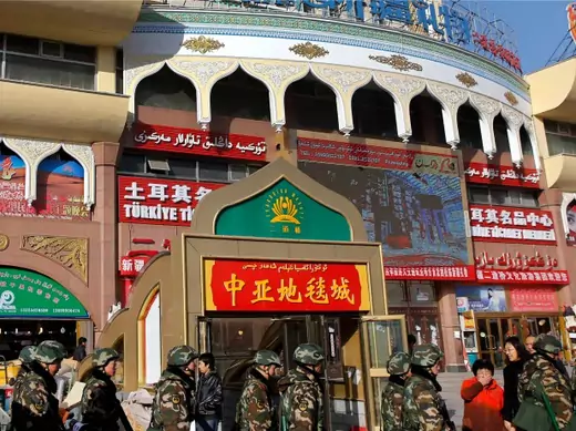 Paramilitary policemen walk past Erdaoqiao Grand Bazaar in Urumqi, Xinjiang Uighur autonomous region on November 17, 2013 (Rooney Chen).