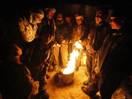 Syrian refugees from the town of Qara gather around a fire to keep themselves warm in a Syrian refugee camp on the Lebanese border town of Arsal, in eastern Bekaa Valley December 12, 2013 (Haju/Courtesy Reuters).