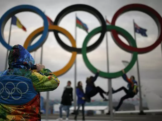 An Olympic volunteer takes pictures of people posing under the Olympic rings in Sochi. (Phil Noble/Courtesy Reuters). 