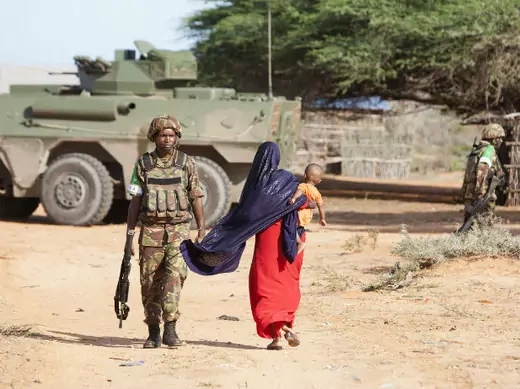 A woman walks by a Kenya Defence Force (KDF) soldier on the outer perimeter area of the Kismayu airport controlled by the African Mission in Somalia (AMISOM), November 11, 2013.