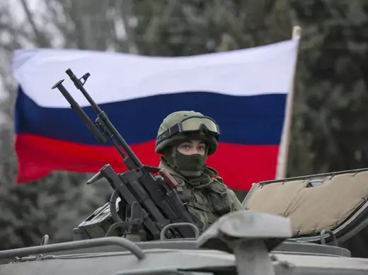 A soldier posted in the Crimean town of Balaclava is seen in front of a Russian flag. (Baz Ratner/ Courtesy Reuters)