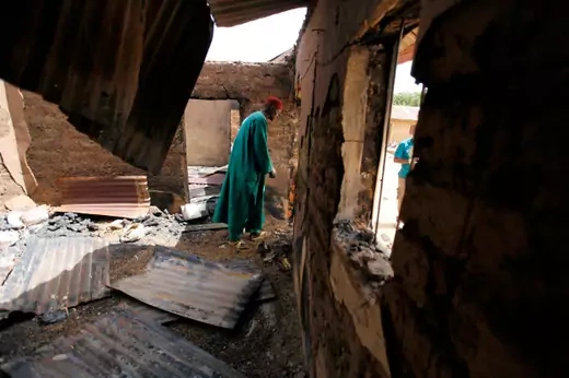 Pius Nna, the village head of Angwan Gata, walks through one of the rooms destroyed when gunmen attacked his village in Kaura local government Kaduna State, March 19, 2014.