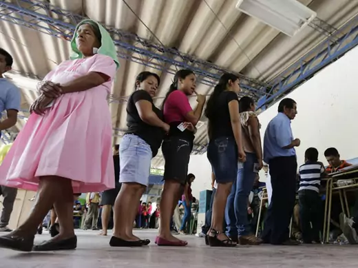 Voters wait in line to cast their vote in a presidential election runoff at a polling station outside in San Salvador