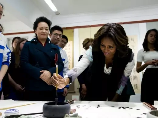 Peng Liyuan, wife of Chinese president Xi Jinping, looks on as U.S. first lady Michelle Obama writes calligraphy in a class at the Beijing Normal School on March 21, 2014. (Andy Wong/courtesy Reuters)