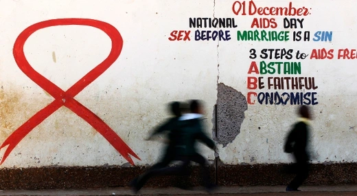 Children run past a mural painting of an Aids ribbon at a school in Khutsong Township, 74 km (46 miles) west of Johannesburg, August 22, 2011