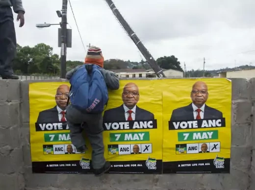 African National Congress (ANC) election posters featuring images of South Africa's President Jacob Zuma are displayed on a wall as a school boy climbs over it in Embo May 6, 2014.