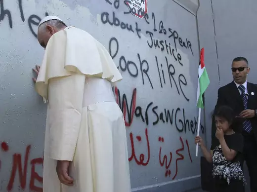 Pope Francis touches the wall that divides Israel from the West Bank, on his way to celebrate a mass in Manger Square next to the Church of the Nativity in the West Bank city of Bethlehem May 25, 2014 (Amareen/Courtesy Reuters).