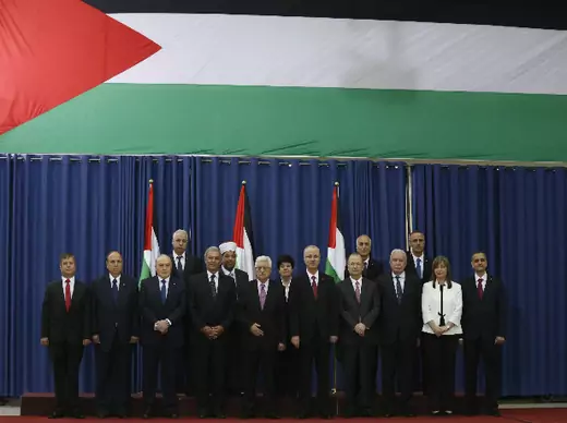 Palestinian prime minister Rami Hamdallah (6th L) and Palestinian president Mahmoud Abbas (5th L) pose for a group photo with Palestinian ministers during a swearing-in ceremony of the technocratic government, in the West Bank city of Ramallah June 2, 2014 (Torokman/Courtesy Reuters).