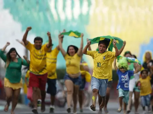 Residents run to celebrate after decorating a street in the colours of Brazil's national flag, ahead of the 2014 World Cup, in the Taguatinga neighbourhood of Brasilia