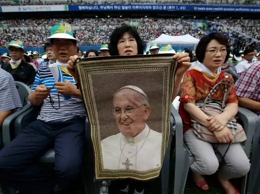 A woman holds a picture of Pope Francis while waiting for his arrival for the Holy Mass at Daejeon World Cup stadium in Daejeon August 15, 2014. Pope Francis on Friday commemorated the more than 300 people killed in a ferry disaster in April, and called on South Koreans, among Asia's richest people, to beware of the spiritual "cancer" that often accompanies affluent societies. REUTERS/Lee Jin-man/Pool (SOUTH KOREA - Tags: RELIGION POLITICS)