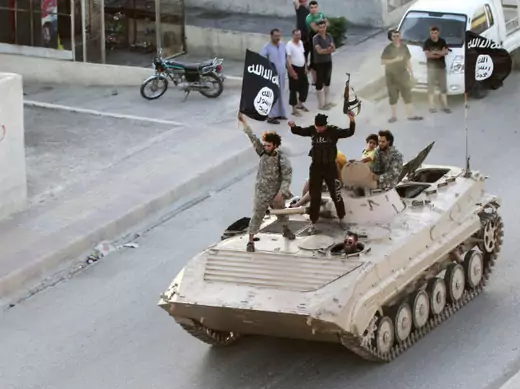 ISIS fighters stand atop a tank during a military parade in Syria's Raqqa province on June 30, 2014. The parade was held to celebrate the group's declaration of a "caliphate" spanning its territory in Syria and Iraq one day earlier.