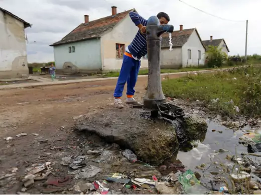 A Roma boy pumps water in the slum of Tiszavasvari, east of Budapest, Hungary, on September 26, 2014.