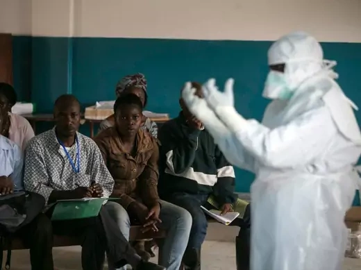 A health worker demonstrates putting on protective gear in a Red Cross facility in the town of Koidu, Kono district in Eastern Sierra Leone, December 2014 (Courtesy Baz Ratner/Reuters). 