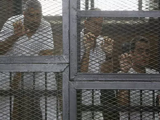 Al Jazeera journalists (L-R) Mohammed Fahmy, Peter Greste and Baher Mohamed stand behind bars at a court in Cairo May 15, 2014 (Courtesy Reuters).
