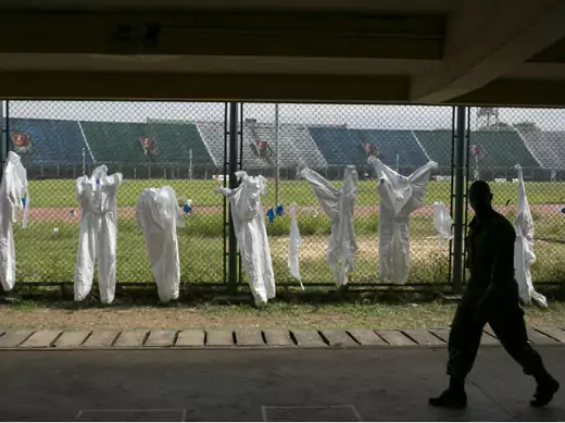 A Sierra Leonean soldier walks past protective clothing drying on a fence in the Ebola Training Academy in Freetown, Sierra Leone, on December 16, 2014.