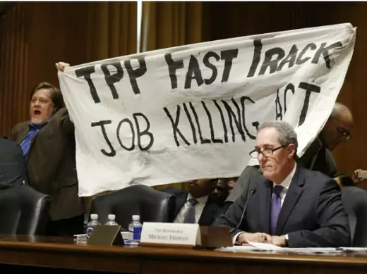 A policewoman removes a man protesting the Transpacific Partnership (TPP) as U.S. Trade Representative Michael Froman testifies before a Senate Finance Committee hearing on January 27, 2015.