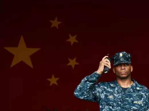 A U.S. Navy servicemen listens to a walkie-talkie in front of a Chinese national flag onboard U.S. aircraft carrier USS George Washington during its port call in the Hong Kong waters June 16, 2014. REUTERS/Bobby Yip (CHINA - Tags: MILITARY POLITICS MARITIME)