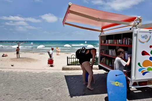 People check books at a new mobile library for beach visitors initiated by the Tel Aviv municipality on the shore of the Mediterranean Sea in Tel Aviv July 9, 2013.