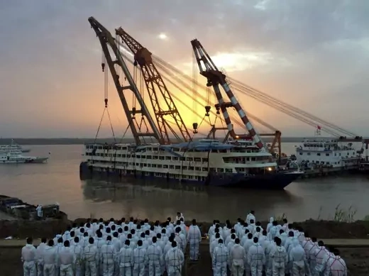 Rescue workers stand on the river bank as the capsized cruise ship Eastern Star is pulled out of the Yangtze against sunset, in Jianli, Hubei province, China, June 5, 2015. Only 14 survivors, one of them the captain, have been found after the ship carrying 456 overturned in a freak tornado on Monday night. A total of 103 bodies have been found. REUTERS/China Daily CHINA OUT.