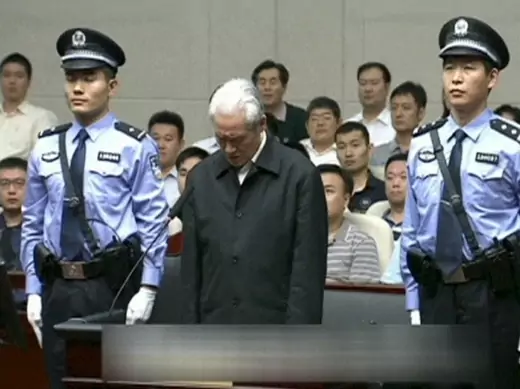 Zhou Yongkang, China's former domestic security chief, stands between his police escorts as he listens to his sentence in a court in Tianjin, China, in this still image taken from video provided by China Central Television and shot on June 11, 2015. According to CCTV, Zhou was sentenced to life imprisonment on Thursday, deprived of his political rights for life and his personal assets confiscated, for accepting bribes, abusing power and deliberately disclosing state secrets, the Tianjin Municipal No. 1 Int