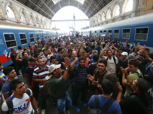 Migrants gesture as they stand in the main Eastern Railway station in Budapest, Hungary, on September 1, 2015.