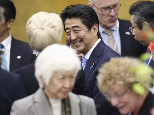 Japan's PM Abe speaks to an attendee during the reception for the World Assembly for Women in Tokyo