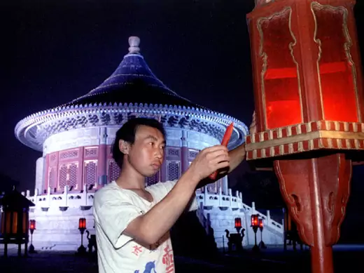 A worker replaces a candle in a lantern in front of The Imperial Vault of Heaven at the Temple of He..