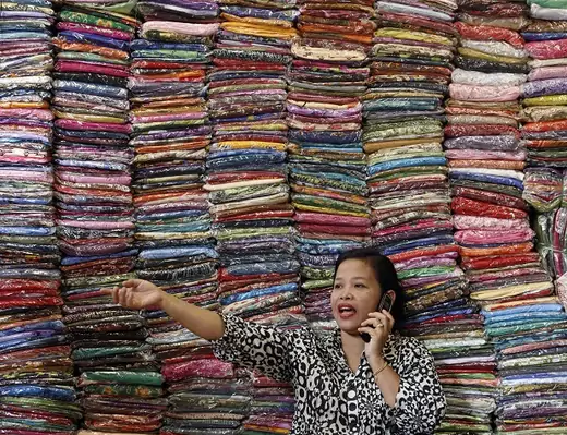 A businesswoman talks to a supplier as she sells cloth at her bazaar in Kuala Lumpur