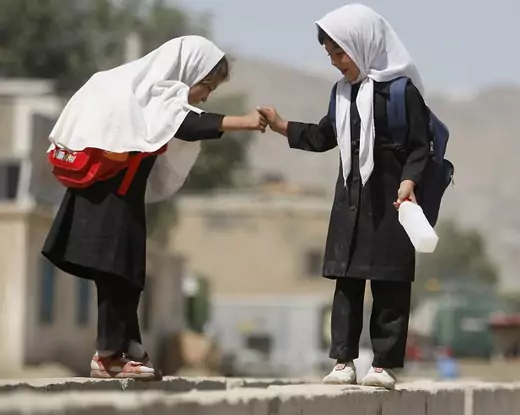 Schoolgirls balance on a wall in Kabul