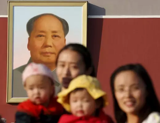 Two women and their babies pose for photographs in front of the giant portrait of late Chinese chairman Mao Zedong on the Tiananmen Gate in Beijing