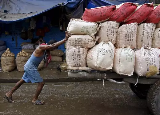 A labourer pushes a handcart loaded with sacks containing tea packets, towards a supply truck at a wholesale market in Kolkata, India, June 26, 2015. For years Indian businesses have lobbied for a nationwide sales tax, hoping to replace a chaotic structure that inflates costs and halts their trucks at state borders for duty payments, and to unify the country into one of the world's largest single markets. But after political compromises that finally got a goods and services tax (GST) bill before parliament