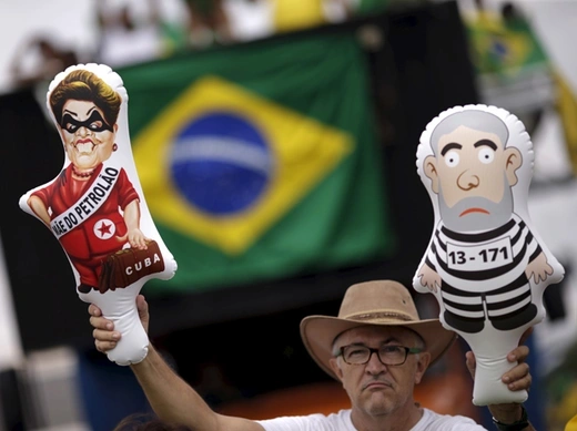A demonstrator holds inflatable dolls depicting Brazil's former president Lula da Silva and Brazil's President Rousseff during a protest calling for the impeachment of Rousseff near the National Congress in Brasilia