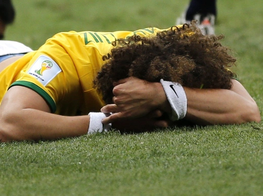 Brazil's David Luiz lies on the pitch after missing a goal during the 2014 World Cup third-place playoff between Brazil and the Netherlands at the Brasilia national stadium