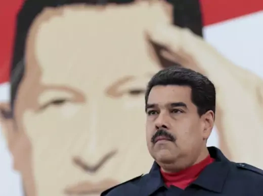 Venezuela's President Nicolas Maduro stands in front of an image depicting the country's late President Hugo Chavez during a meeting with members of Venezuela's United Socialist Party (PSUV) in Caracas