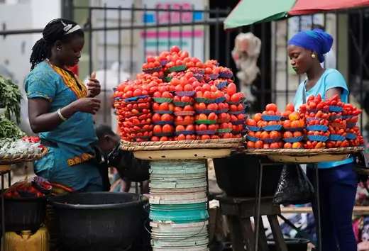 Women arrange produce for sale at a roadside market in Ojodu district in Lagos