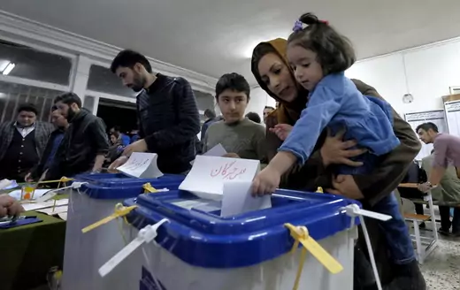 Iranian woman holding her daughter casts her ballot during elections for the parliament and Assembly of Experts, in Tehran