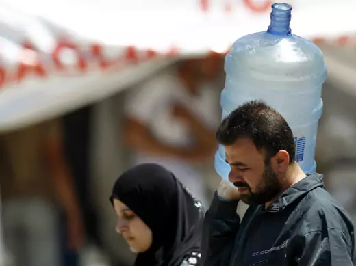 A Syrian man carries a water container as he is accompanied by a woman at a refugee camp in the Turkish border town of Yayladagi (Reuters/Umit Bektas)
