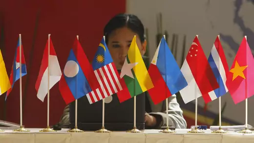 A woman sits in front of flags of ASEAN members in Bali, Indonesia, November 16, 2011.