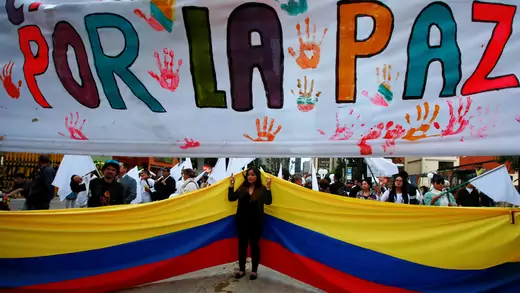 A supporter rallying for a peace agreement between the Colombian government and FARC stands under a banner reading "for peace" during a march in Bogota.