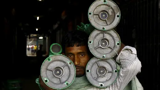 A laborer carries iron hand pumps through an alley at a wholesale market in Kolkata.