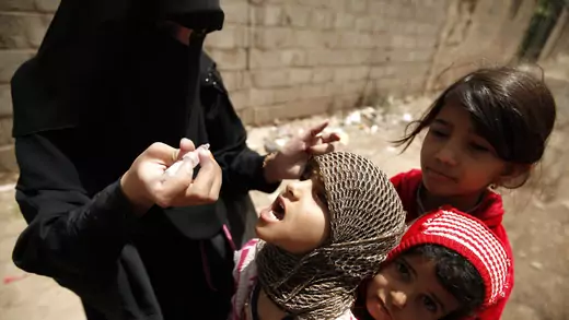 A health worker administers drops of polio vaccine to children in an outskirt of the Yemeni capital Sana'a.