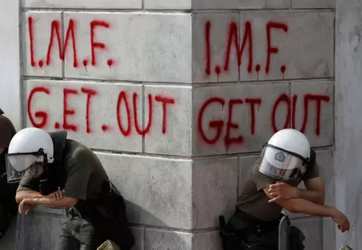 Greek riot policemen rest in front of graffiti written on the wall of a bank in Athens during violent demonstrations over austerity measures demanded by the May 2, 2010, EU-IMF bailout.  Yiorgos Karahalis/Reuters 