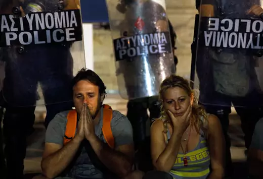 Municipal public school guard Yiorgos Avramidis and a colleague, who lost their jobs due to government budget cuts, sit in front of a police line guarding the Greek parliament on July 17, 2013. Yannis Behrakis/Reuters