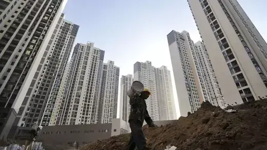 A construction worker walks among high-rise apartment blocks in China’s Hubei Province.