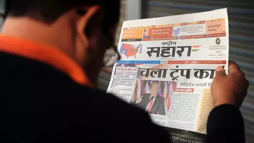 An Indian man reads a newspaper article about newly elected U.S. President Donald J. Trump, on a street in Allahabad. 