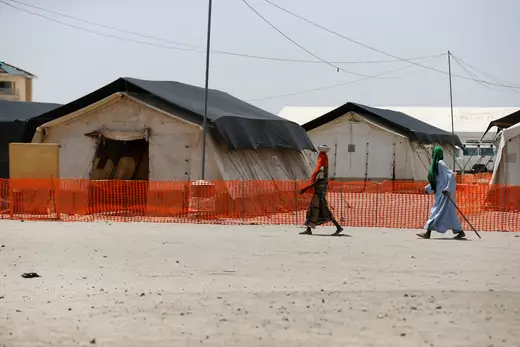 Two people walk past World Food Program tents in Northern Nigeria.