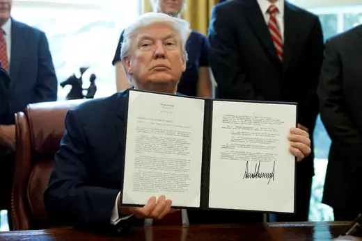 U.S. President Donald Trump holds up a directive ordering an investigation into the impact of foreign steel on the American economy after signing it.