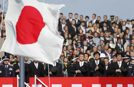 Japanese Prime Minister Shinzo Abe salutes Japan's national flag as he reviews Japan Self-Defence Forces troops during an annual ceremony at Asaka Base in Asaka on October 27, 2013. 