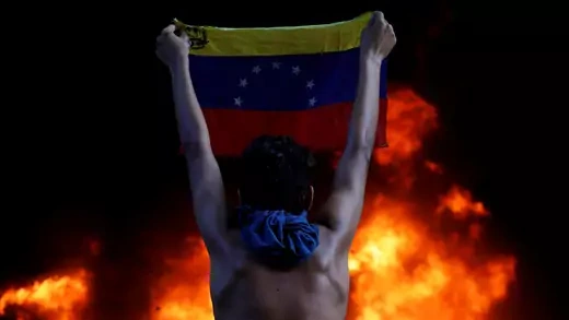 A protestor holds a national flag while standing in front of a fire during a rally against Venezuela's President Nicolas Maduro, in Caracas, Venezuela, on June 12, 2017. (Carlos Garcia Rawlins/Reuters)