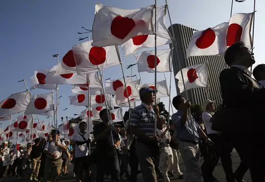 Members of the nationalist movement "Ganbare Nippon" march with Japanese national flags while paying tribute to the war dead near Yasukuni Shrine in Tokyo August 15, 2013.